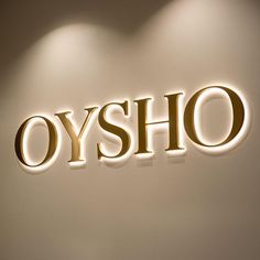 the sign is lit up on the wall in front of the light that says, oysho