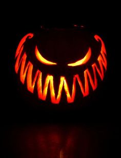 a carved pumpkin sitting on top of a table with its eyes glowing in the dark