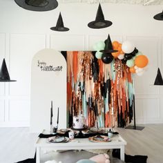 a party with balloons and decorations on the table in front of an art work display