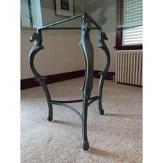 a glass table with metal legs in a room