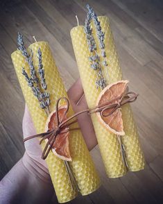 two candles made out of beeswap and lavenders are held in the palm of a person's hand