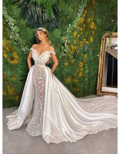 a woman standing in front of a green wall wearing a wedding dress