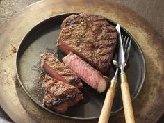 two steaks on a plate with a fork and knife