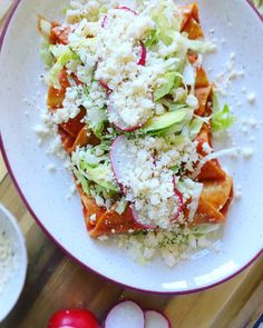 a white plate topped with lots of food next to radishes and cucumbers