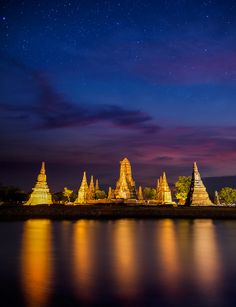 the night sky is reflected in the water and lights shine brightly on the temple's spires