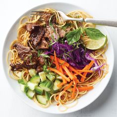 a white plate topped with meat and veggies next to a fork on top of a table