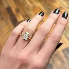 a woman's hand with black fingernails and a gold ring on top of her finger