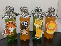 four bottles filled with different types of liquid and animals on top of each bottle are wrapped in brown paper