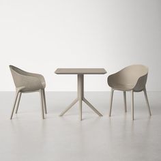 two chairs and a table in an empty room with one chair facing the other way