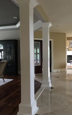 an empty living room with white columns and hard wood flooring