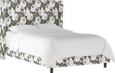 an upholstered bed with white and pink flowers on the headboard is shown