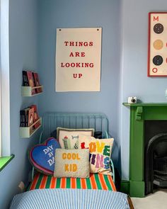 a bedroom with blue walls and colorful bedding in front of a green fire place