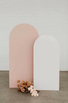 two large white and pink shapes next to each other with flowers on the ground in front of them