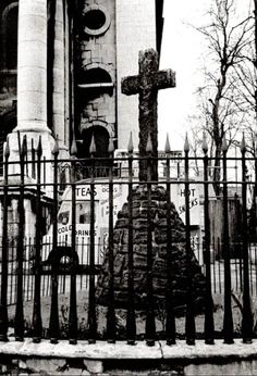 a black and white photo of an old church with a cross on the front gate