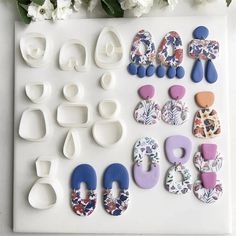 various shapes and sizes of buttons sitting on a table next to white flowery stems