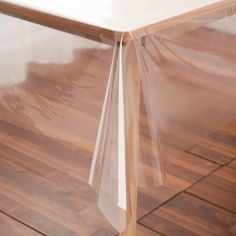 a table with clear plastic covering on it's top and wood flooring in the background