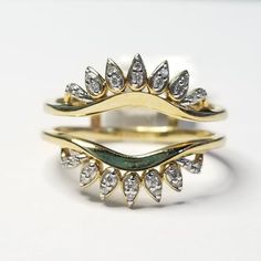 two gold rings with white diamonds on top and green stone in the middle, sitting next to each other