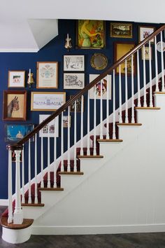 there is a stair case with pictures on the wall and below it, along with other framed artwork