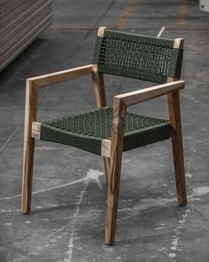 a green chair sitting on top of a cement floor next to a wooden armrest