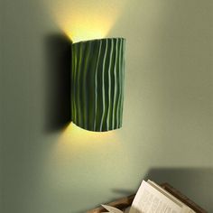 a lamp that is on the side of a wall next to a box with an open book