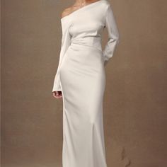 a woman wearing a white dress with long sleeves and an off the shoulder neckline