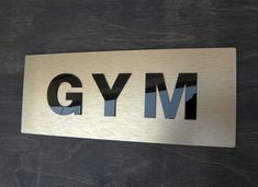 a metal sign that says gym on the side of a door with black letters and silver lettering