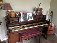 there is a piano in the living room next to a lamp and pictures on the wall