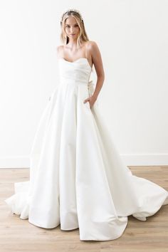 a woman in a white wedding dress posing for the camera with her hands on her hips