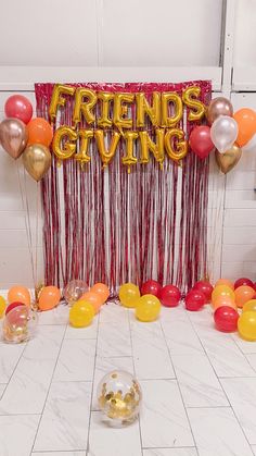 balloons and streamers are on the floor in front of a sign that says friends giving