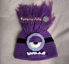 a crocheted purple hat with an evil face on it