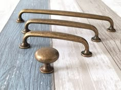 three antique brass handles on a white painted wood floor