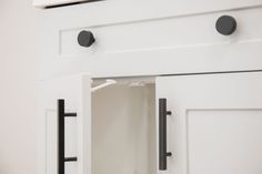 a white cabinet with black handles and knobs