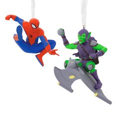 two ornaments are hanging from strings in the shape of spiderman and green man