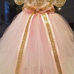 a pink and white dress with gold sequins on the top, sitting on a table