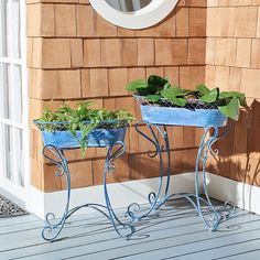 two blue planters sitting on top of a wooden floor next to a building with a round window