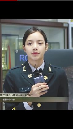 a woman in uniform is holding a cell phone and looking at the screen with her hand