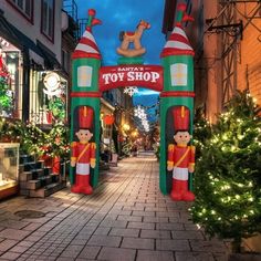 an inflatable toy shop entrance with christmas trees and lights on the side walk