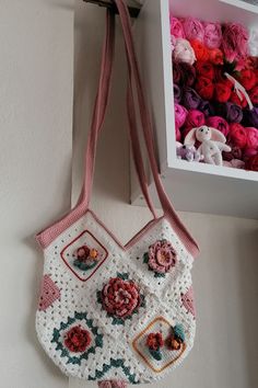 a crocheted purse hanging on the wall next to a box of yarns