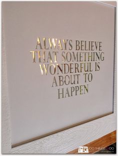 a white wall with gold foil on it that says, always believe that something wonderful is about to happen