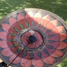 a metal plate with an orange flower design on it and a black stick sticking out of the top