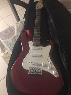 a red electric guitar sitting on top of a black case