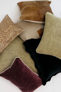 several pillows are stacked on top of each other in different shapes and sizes, including leopard print