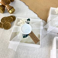 two small white boxes with buttons and ribbons on the top one has a flower in it