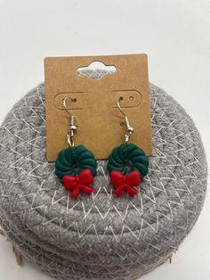 a pair of green and red flower earrings on top of a gray cushioned surface