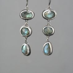 "These eye catching dangle earrings feature a row of three natural rose cut labradorite stones. They are a lovely soft grey with fascinating flashes of green and blue. They are lovingly set in handmade sterling silver bezel settings with sterling french ear wire. The silver has an oxidized finish with areas of high shine to create contrast.  The earrings measure 2 1/2\" from top to bottom." Labradorite Earrings, Dope Jewelry, Jewelry Lookbook, Funky Jewelry, Gem Stones, Stone Work, Jewelry Inspo, Dream Jewelry, Ear Jewelry