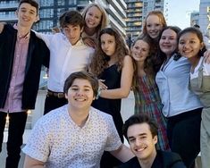 a group of people standing next to each other in front of tall buildings and skyscrapers