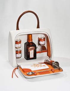 an orange and white handbag with bottles in the inside, on a white surface