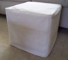 a white square ottoman sitting on top of a carpeted floor