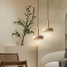 three lights hanging from the ceiling in a living room with a couch, chair and potted plant