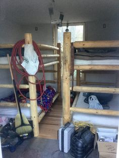 bunk beds in a small room with wooden posts and mattresses on the bottom floor